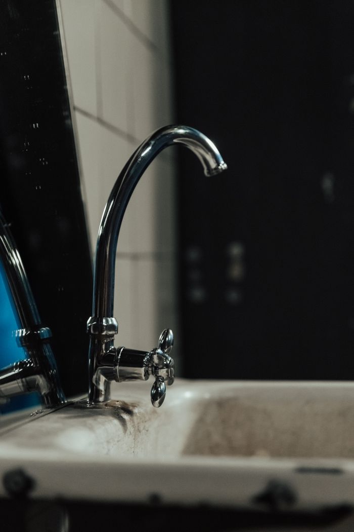 Close-up of an old-fashioned bathroom sink with a chrome faucet and vintage tiles.